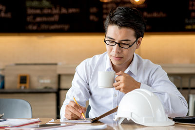 Man holding coffee cup while working on table at cafe