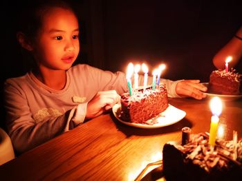 Girl looking at birthday cake in darkroom