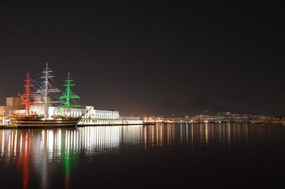 Illuminated ship sailing in river against clear sky at night