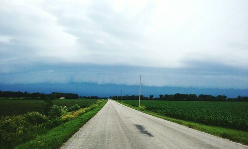 Road amidst field against sky