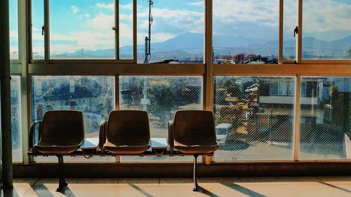 Empty chairs near window at train station