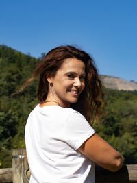 Portrait of smiling young woman standing against clear sky