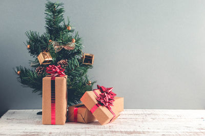 Close-up of christmas tree and presents against gray wall