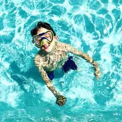 High angle view of boy wearing swimming goggles standing in pool
