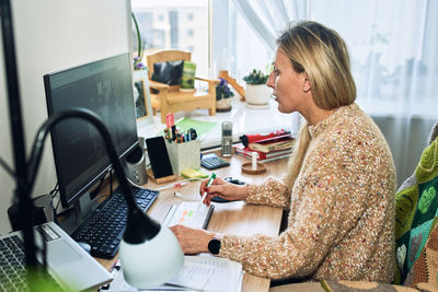 Side view of woman using computer at home