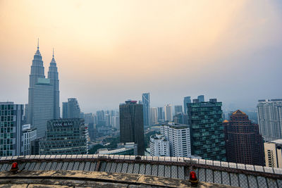 Modern buildings in city against sky during sunset