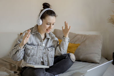 Angry and dissatisfied woman with casual clothes sitting on bed at home with computer and studying