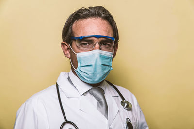 Portrait of doctor wearing mask against colored background