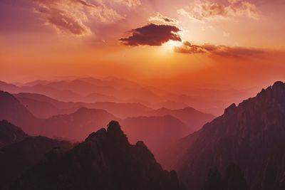 Scenic view of silhouette mountains against orange sky