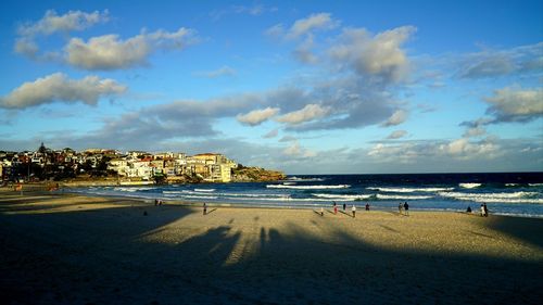 People on beach against sky in city