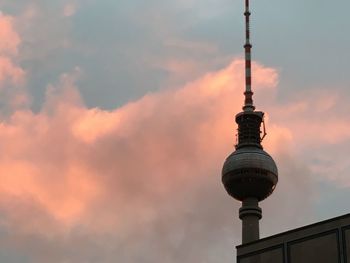 Low angle view of communications tower against cloudy sky