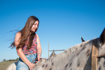 Low angle view of smiling woman against clear blue sky