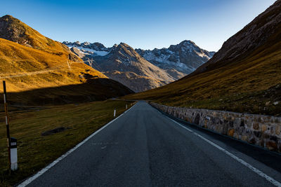 Empty road leading towards mountains against sky