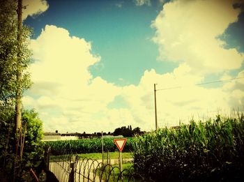 View of field against cloudy sky