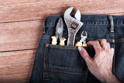 Cropped hand holding work tool in jeans pocket