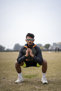 Portrait of young man exercising on field