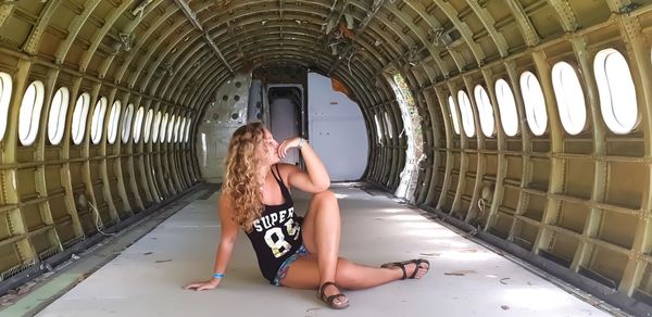 Full length of young woman sitting in abandoned airplane