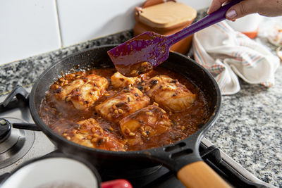 Close up of frying pan with cod and tomato sauce.