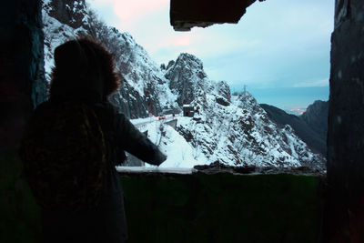 Rear view of man standing on snow covered mountain