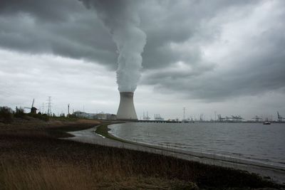 Smoke stack by factory against sky