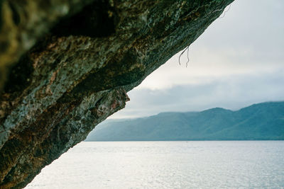 Scenic view of sea by mountains against sky