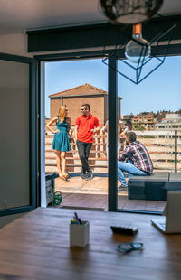 View of colleagues talking in rooftop through a coworking office door