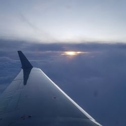 Airplane wing against sky during sunset