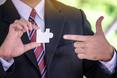 Midsection of businessman holding puzzle piece