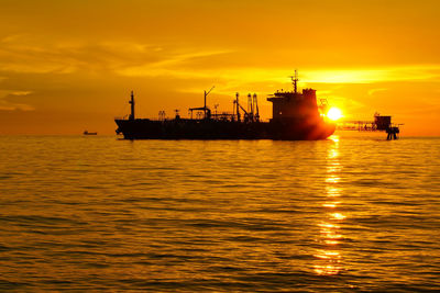 Silhouette ship on sea against sky during sunset