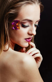 Close-up of beautiful young woman against black background