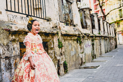 Girl wearing dress standing against wall