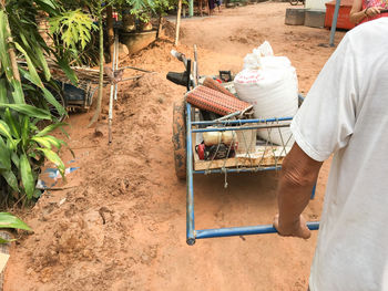 Cropped image of man pushing cart on dirt road