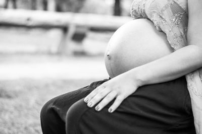 Midsection of pregnant woman sitting outdoors