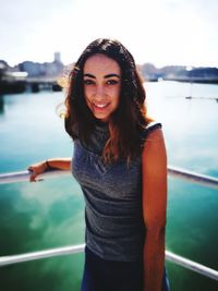 Portrait of smiling young woman standing against river