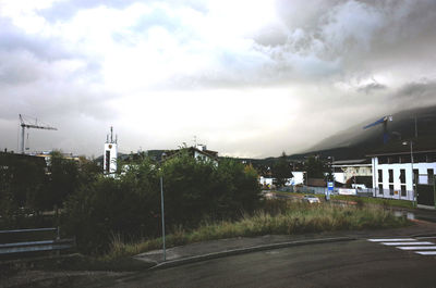 Road by city against cloudy sky