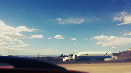 Cars on road against cloudy sky