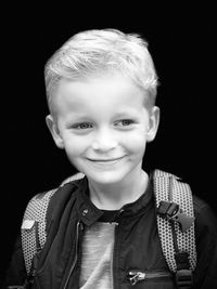 Portrait of smiling boy against black background