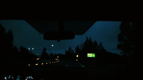 Silhouette trees against blue sky at night