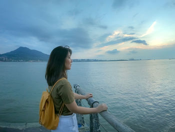 Young woman standing in sea against sky