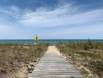 Boardwalk at beach against sky