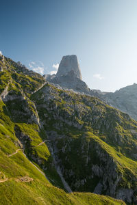 View of mountain in the background during hike. green grass and dirt path  leading to it.