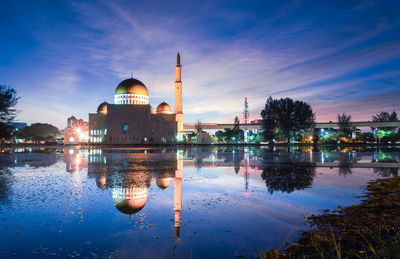 Lake by masjid as-salam against sky at dusk
