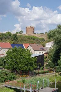 Houses by trees and buildings against sky