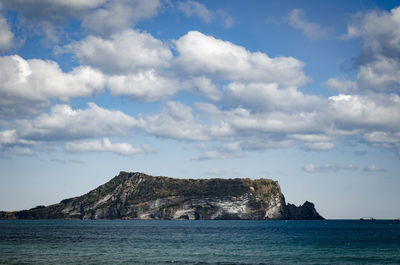 Scenic view of sea and rocks against cloudy sky