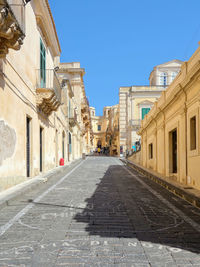 Empty road along buildings