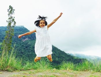 Full length portrait of girl jumping on field