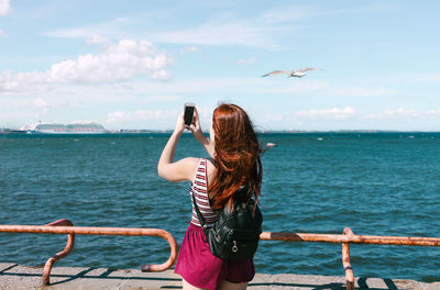 Rear view of woman looking at sea against sky