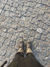 Low section of person standing on cobblestone street