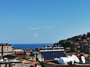 Buildings by sea against blue sky