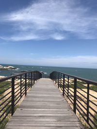 Empty pier over sea against sky